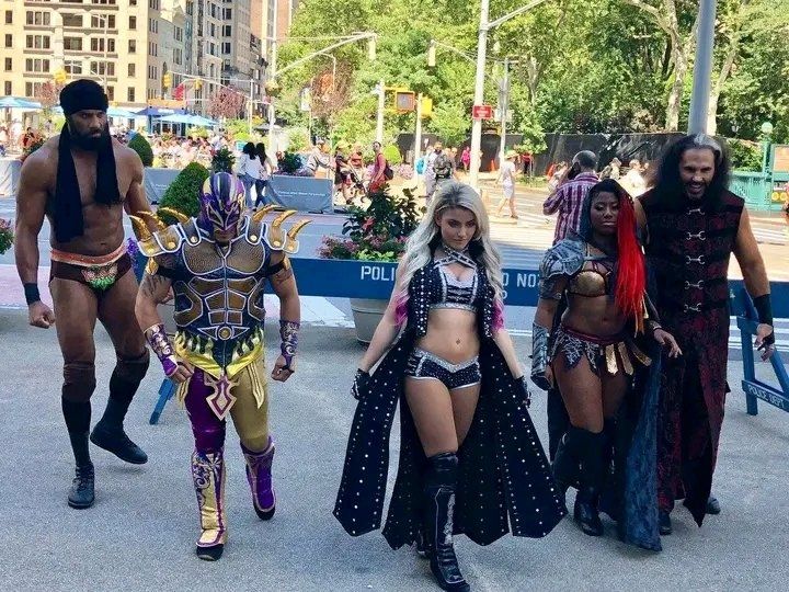 A group of five professional wrestlers walking in public in their gear. From left to right its Jinder Mahal, Kalisto, Alexa Bliss, Athena and Matt Hardy(i am using the ring names i most associate with them)