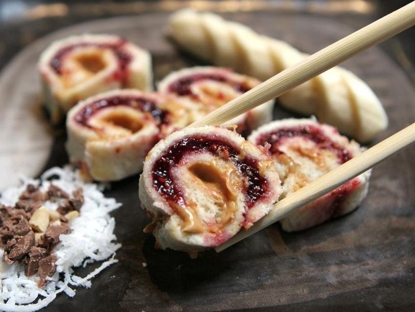 Peanut butter and jelly sushi made with bread and chocolate and coconut on the side 