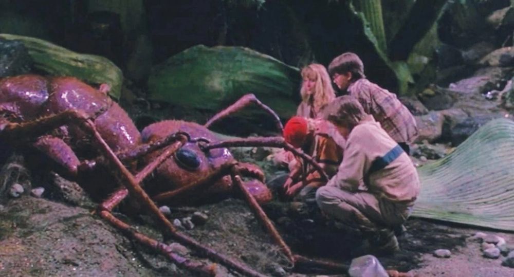 Screencap from the movie honey I shrunk the kids showing the kids all shrunk down hunkered around the dead or dying giant ant