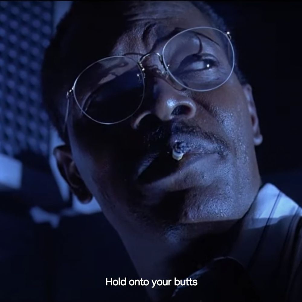Still from the movie Jurassic Park showing a close up of Samuel L. Jackson with a cigarette in his mouth. Text reads 