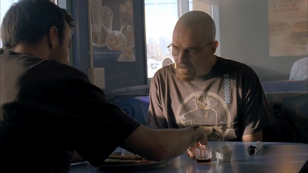 Still from the television show Breaking Bad showing Walter looking at Jesse at a restaurant booth. Jesse has his hand on the table and Walter looks incredulous. Its from the "what the hell are you talking about" meme.