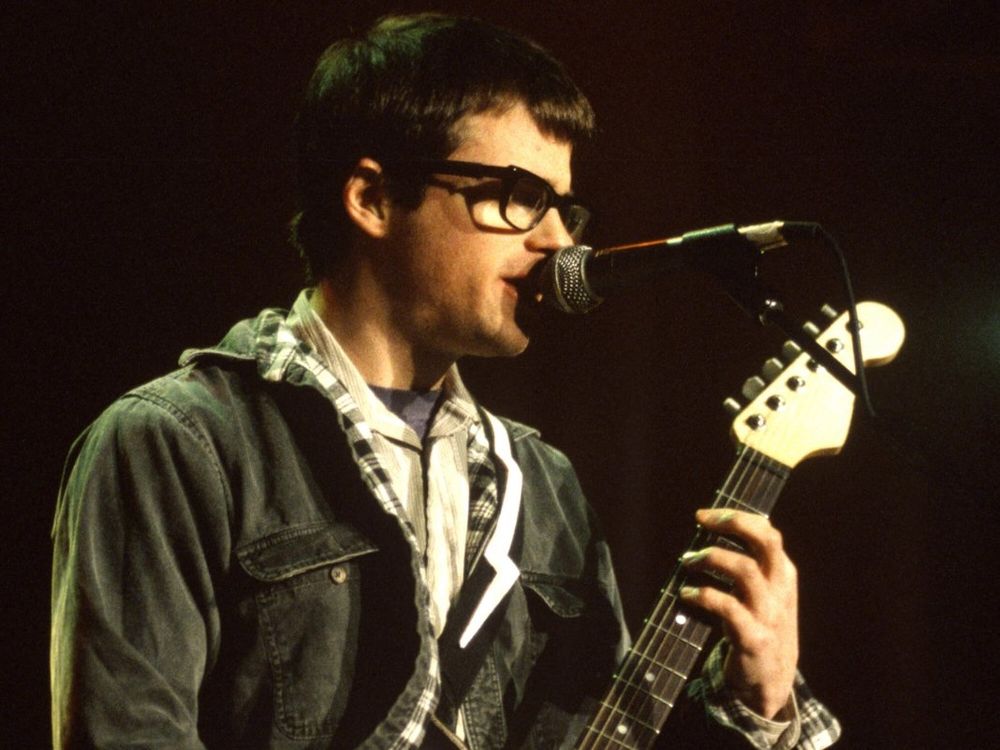 Weezer front man Rivers Cuomo playing guitar and singing 