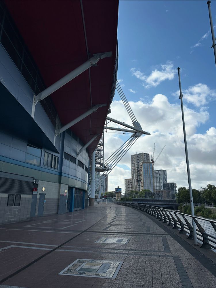 A paved pathway with the Principality Stadium on the left and the River Taff on the right