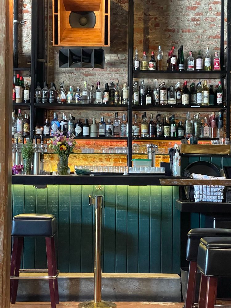 The bar in question. Moody green panels, some fresh flowers, and lots of tasty alcohols.