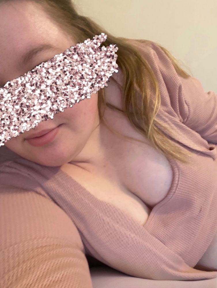 Selfie of Charlotte wearing a dusty pink coloured lounge set. She is propped on her side on a pillow. Her cleavage is showing. She is smiling softly and her face is gently turned to the side slightly. A sparkly pink sticker has been added to cover her eyes.