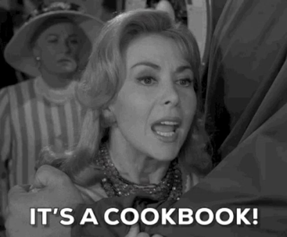 a woman is holding a man 's hand and says `` it 's a cookbook '' .