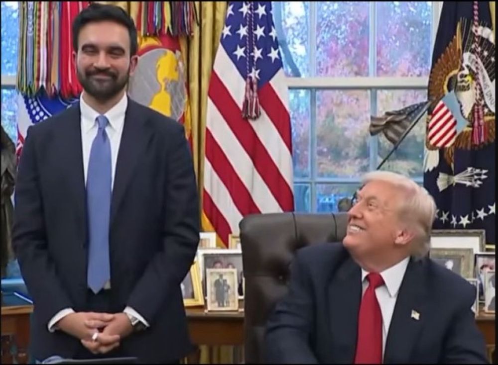 Trump looks up to Mamdani with a large grin on his face