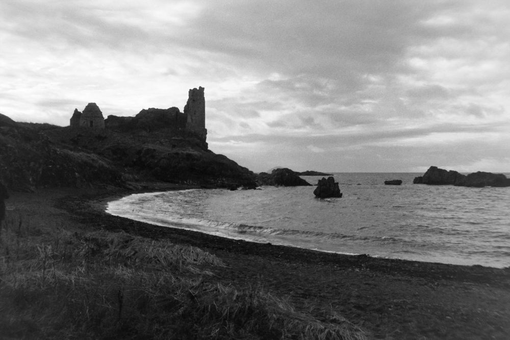 A black and white photograph of a castle on a cliff overlooking the sea