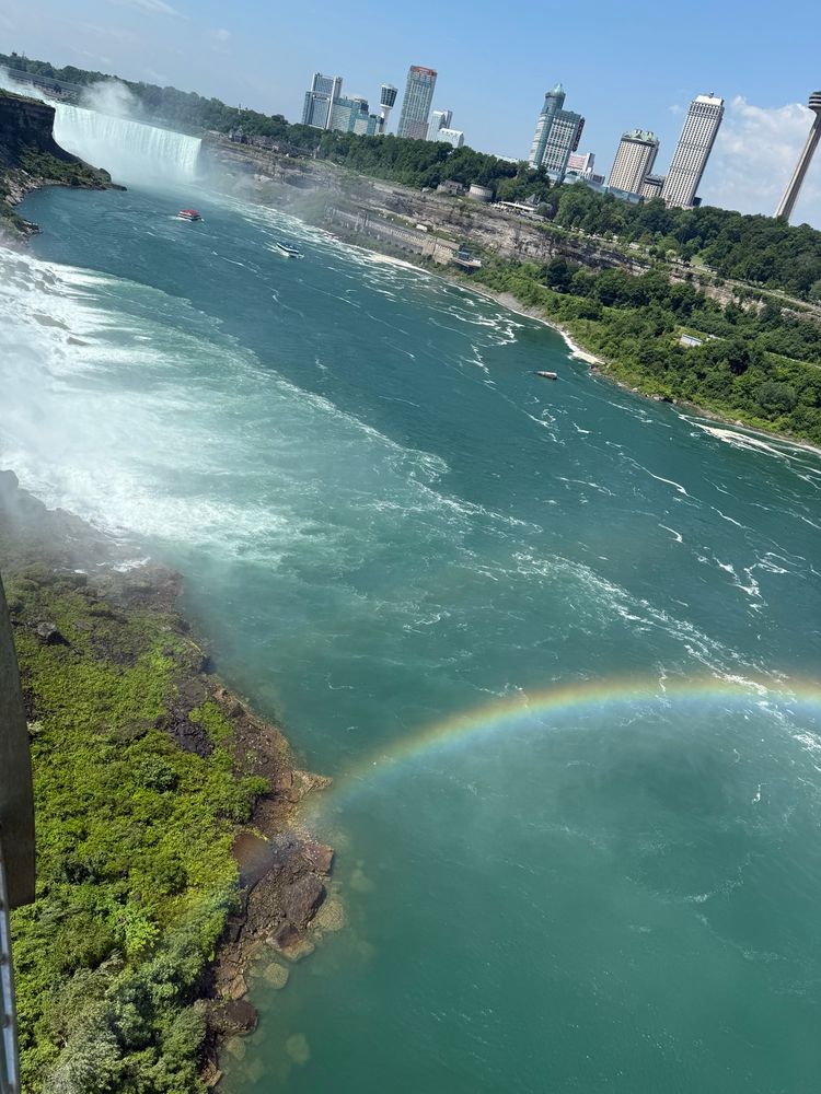 Rainbow over a body of water with Niagara Falls in the background. 