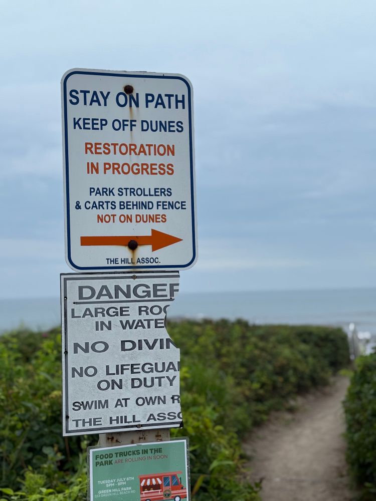 Beach signs saying “stay on path keep off dunes restoration in progress.” 