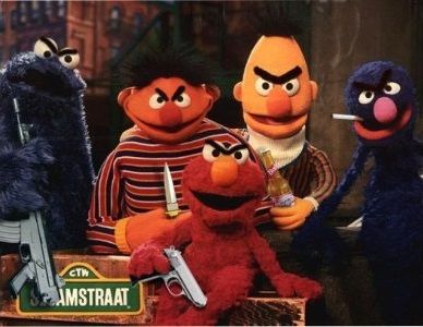 Ancient (by Internet standards) obviously-edited image of Sesame Street characters posing together on the outdoorsy set, with a foreign-language version of the Sesame Street sign visible (SESAMSTRAAT), either originating from or popularized by the Bert Is Evil website which (in?)famously posted joke images of Bert either brandishing weapons or posing in photos alongside famously evil political figures like Hitler and...Osama Bin Laden (it was just after 9/11 when the site took off).

From left: Cookie Monster, Ernie, Bert, Grover in the back, with Elmo front and center. 

All five have obviously fake angry-eyebrows crudely added to their faces in MS Paint, each holding either a weapon or a drug: Cookie Monster holding a large gun by its barrel, pointed up (I do not know my guns but wouldn't be surprised if it were an AK-47 given the "evil" theming); Ernie holding out a pocket knife, blade pointed upward; Elmo wielding a smaller pistol-sized gun, pointed downward; Bert holding a bottle of beer; and a cigarette hanging out of the side of Grover's mouth.

See for additional context: https://knowyourmeme.com/memes/bert-is-evil