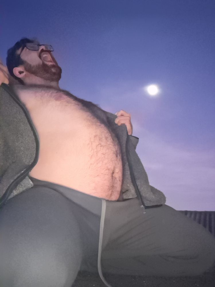 Gordo peludo de óculos ajoelhado arrancando a blusa dramaticamente à luz do luar