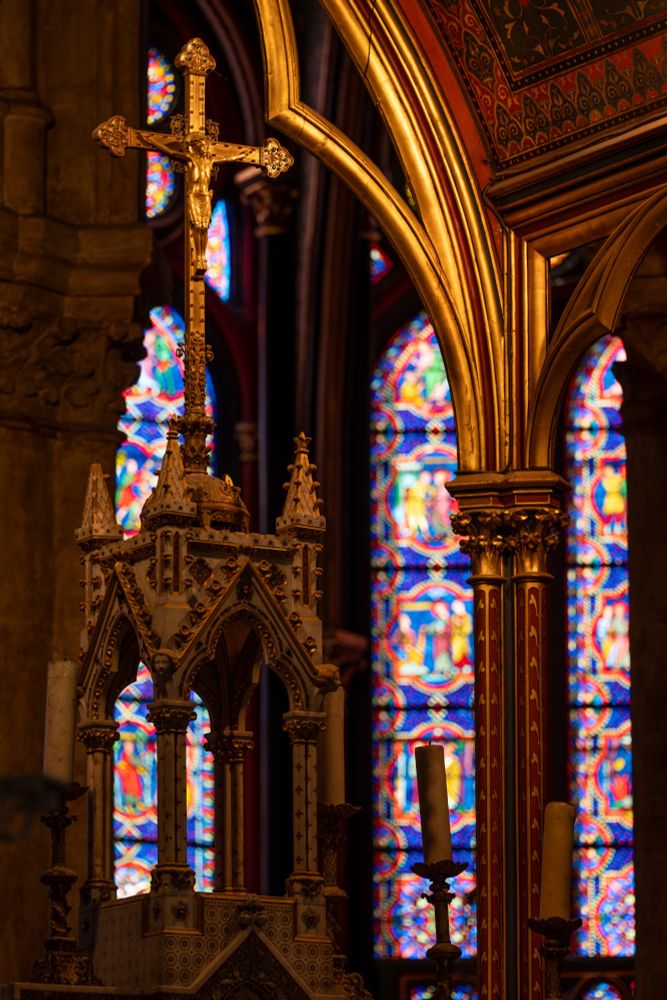 The cathedral alter in gold shown against the stained-glass windows beyond