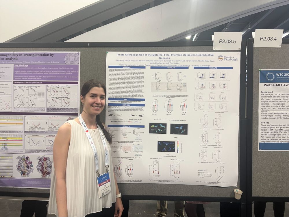 Dr. Riwa Kanj wearing a white flowy tank top, standing in front of her research poster presentation.