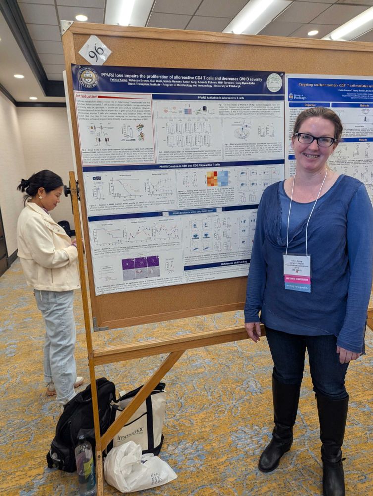 Felicia Kemp is a woman with glasses wearing dark jeans, tall boots, and a blue long-sleeved blouse, smiling. She is standing next to her poster presentation entitled "PPAR loss impairs the proliferation of alloreactive CD4 T cells and decreases GVHD severity".