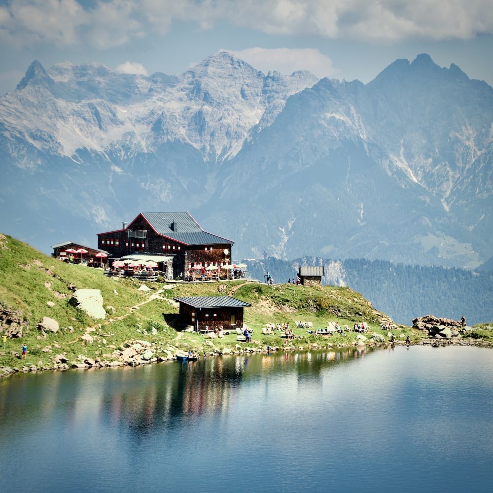 Wildseelodersee mountain lake with Wildseeloderhaus alpine hut on hillside, dramatic Loferer Steinberge mountain range in background, summer hiking destination Tyrol Austria 2018.
