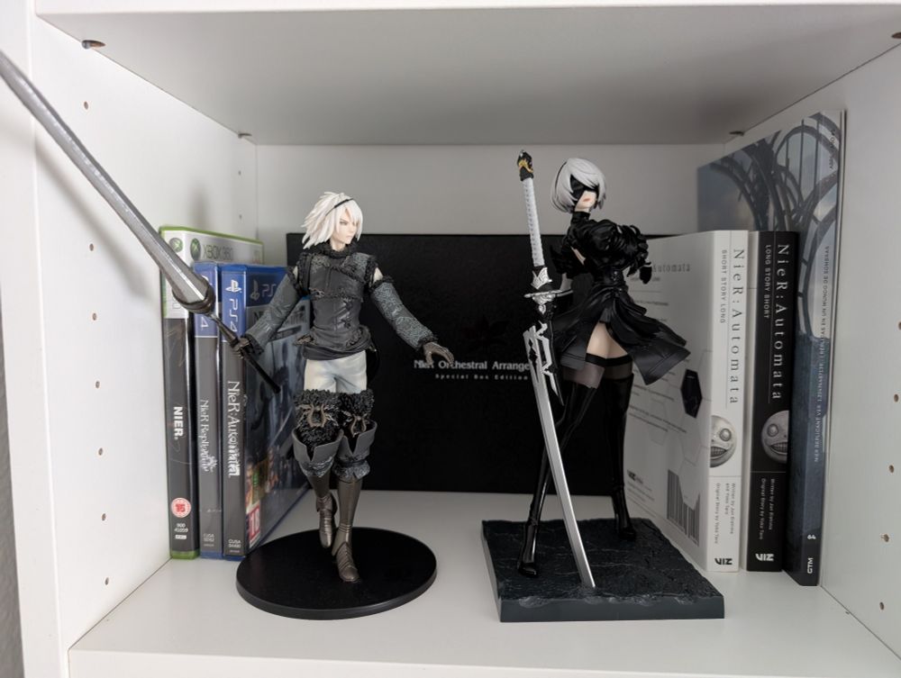 Estantería con juegos, libros, música y figuras de la franquicia NieR. 