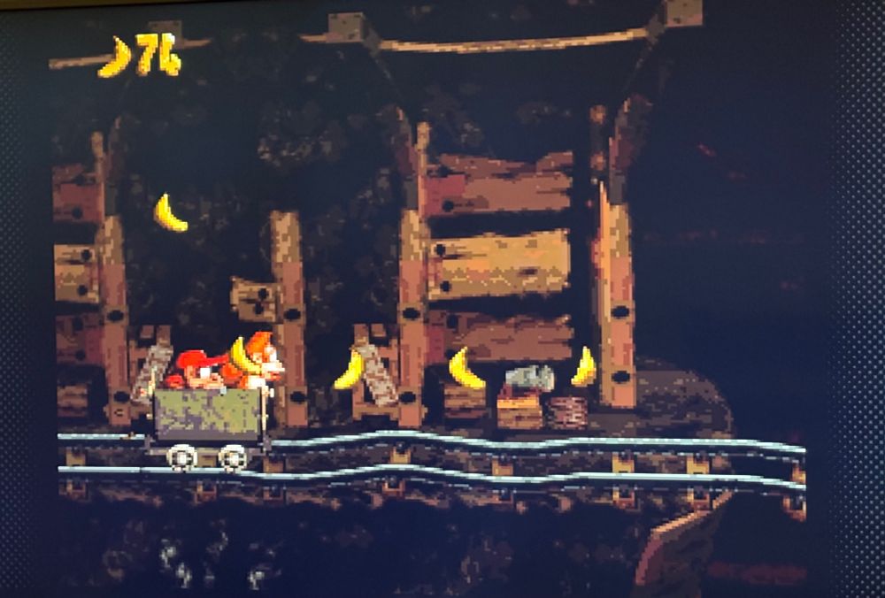 Frame do jogo Donkey Kong para Super Nintendo, com os dois macacos protagonistas em um carrinho de mineração dentro de uma caverna, coletando bananas