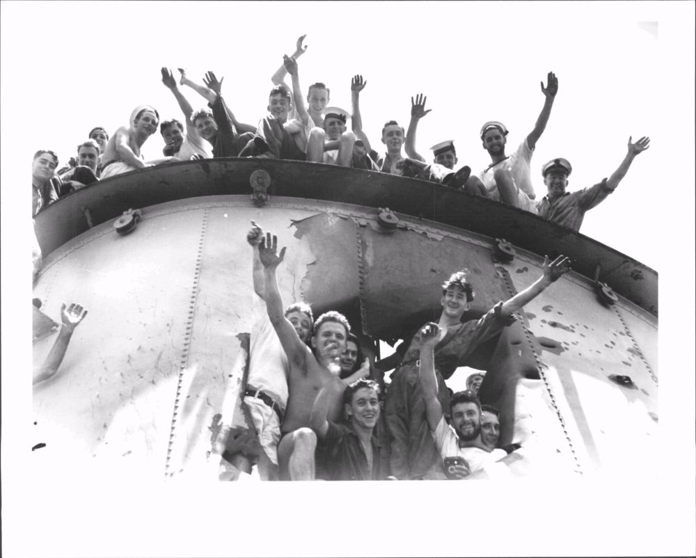Sailors from HmaS Sydney waving and smiling for a photo.