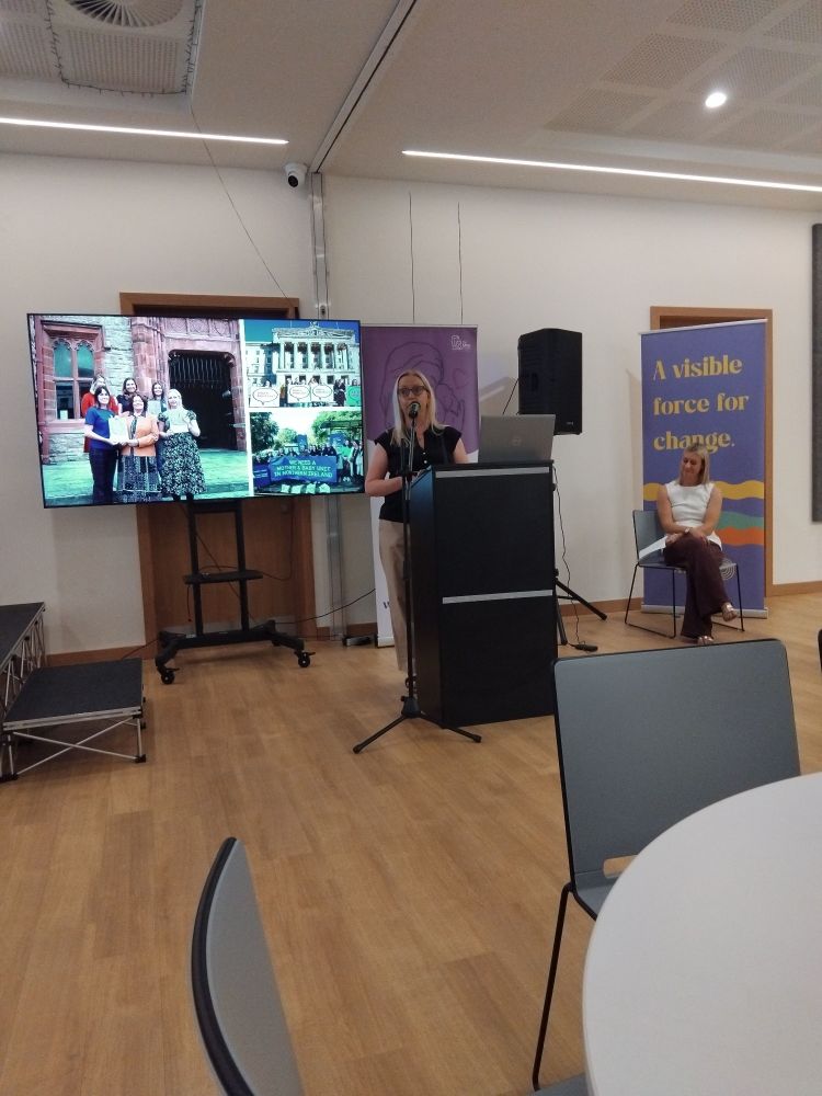 Clare in front of a slide of campaigning images.