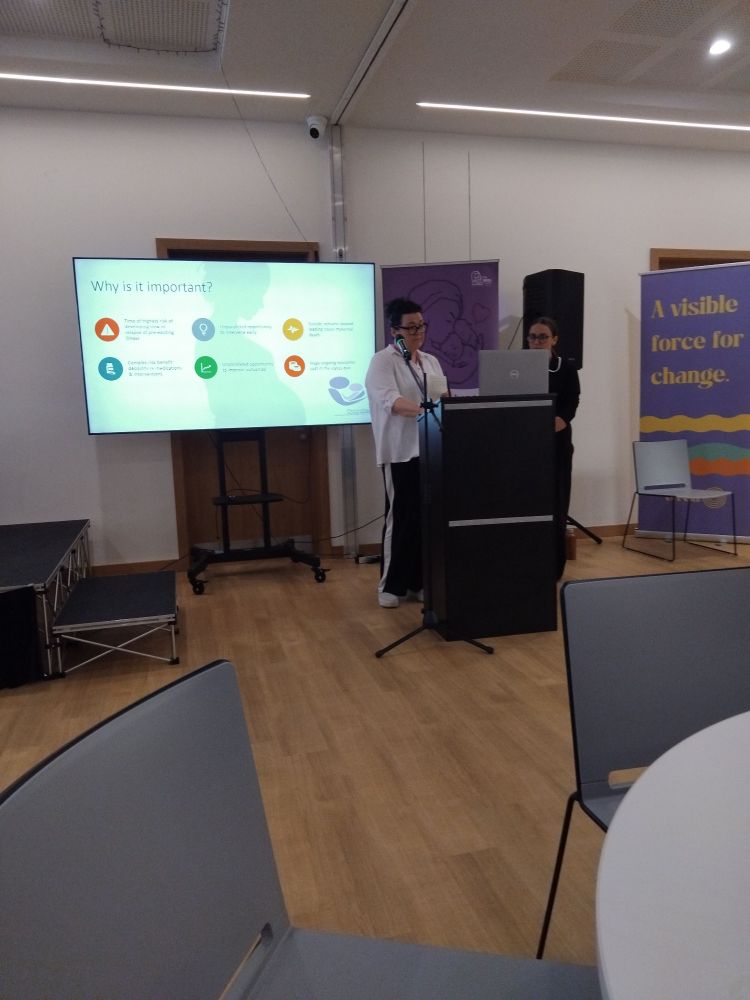 Two women standing in front of a screen.
