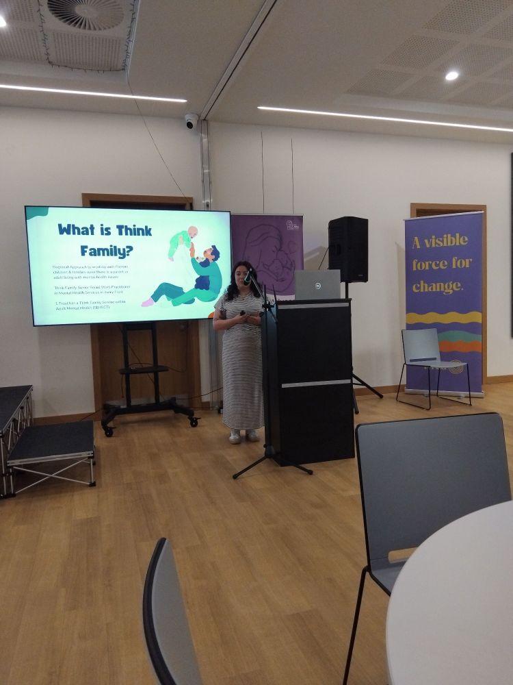 Hannah Brown standing in front of a screen saying "what is Think Family".