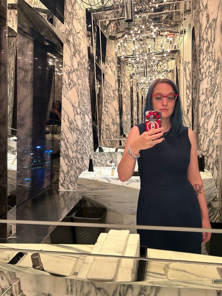 Selfie taken between two mirrors lit by a chandelier, creating an infinity mirror effect.