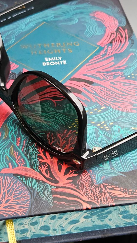 A pair of black ray ban 'new wayfarers' placed on top of a hardback copy of Wuthering Heights