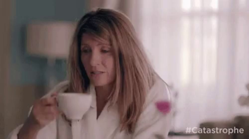 a woman is drinking a cup of coffee in a bathrobe .