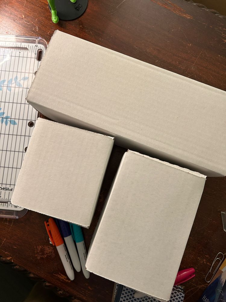 Three white baseball-card boxes with the prototypes for my games On Brand, World Expo, and Fancy Hands inside. They’re so great and fun. 