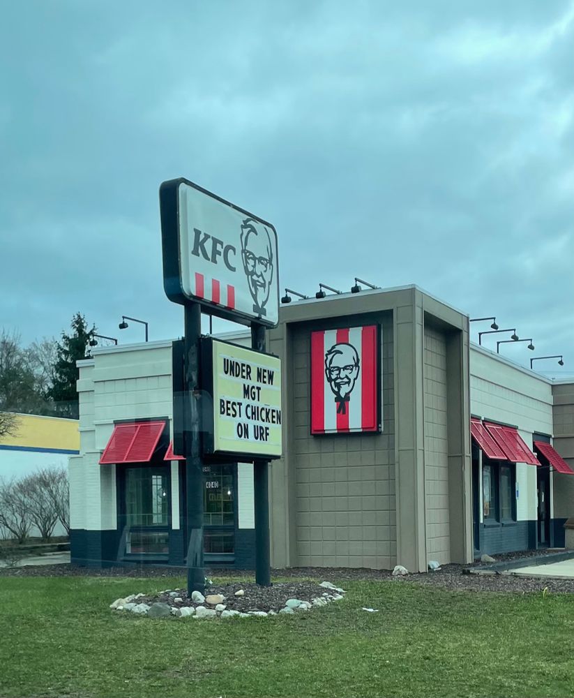 Front side of KFC sign says, “under new mgt best chicken on urf”