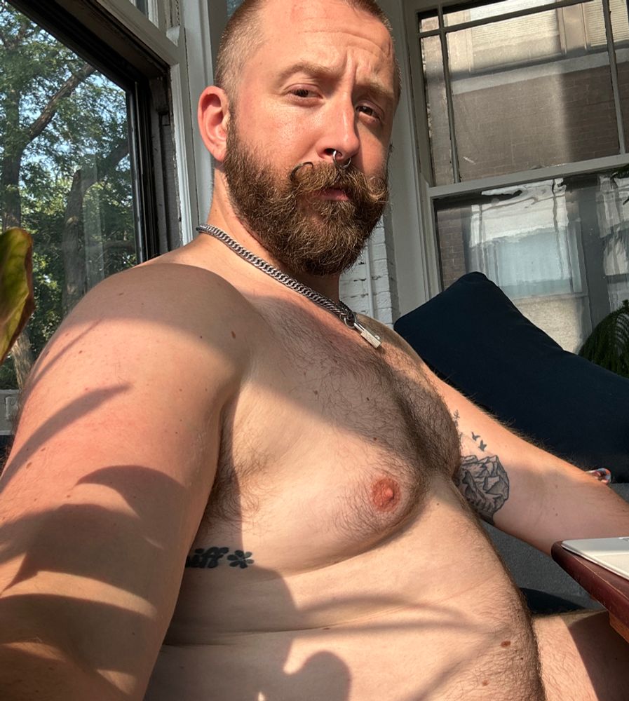 Baldur, sitting in the sun, showing off his chest and belly, with no shirt or pants and unknown whether or not he’s fully naked. But his belly looks beefy. 