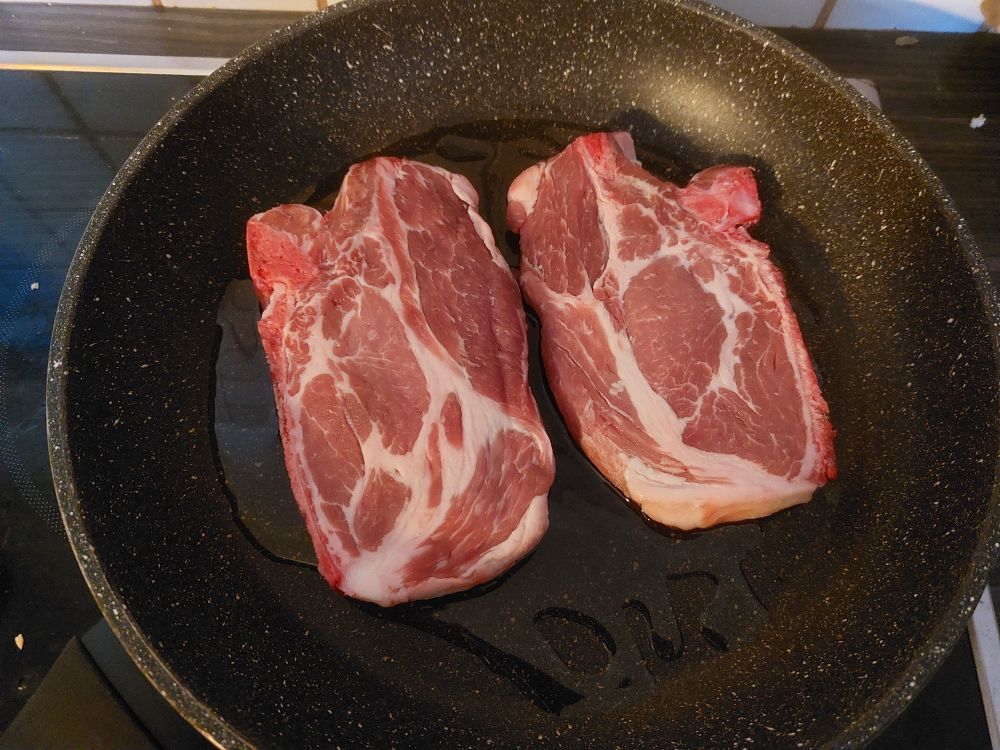 A pan with two still raw steaks in it, ready to be roasted.
