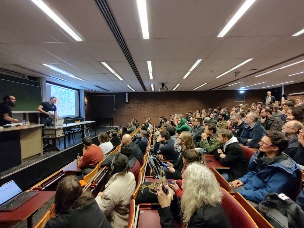 Packed audience hall listening to presentation