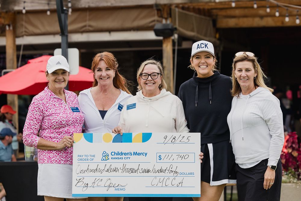 Five individuals posing with a large check made out to Children's Mercy for $11,740 at an outdoor event.