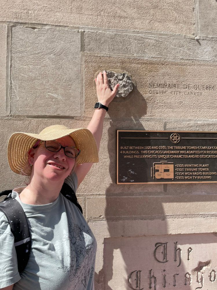I’m facing the camera reaching behind me to touch a chunk of rock labeled “Seminaire de Quebec, Quebec City Canada” that is embedded in the Tribune building in Chicago.
