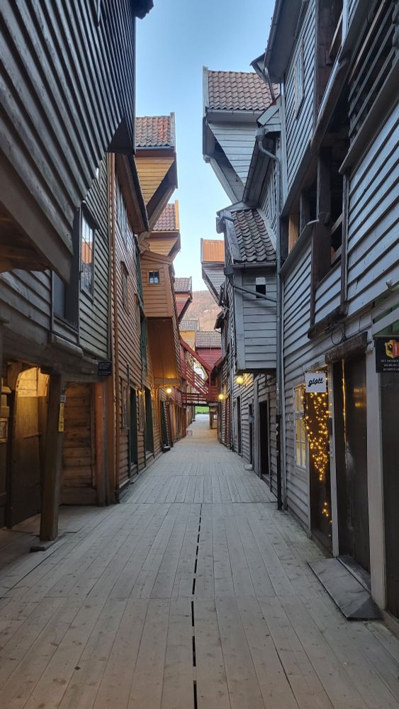 Wooden buildings crowding either side of a narrow walkway in Bergen's Bryggen world heritage site.