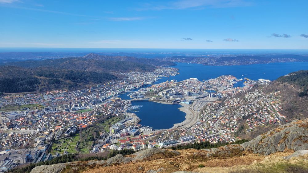 Looking down on the city of Bergen from Ulriken mountain under a blue sky with the sea and islands beyond