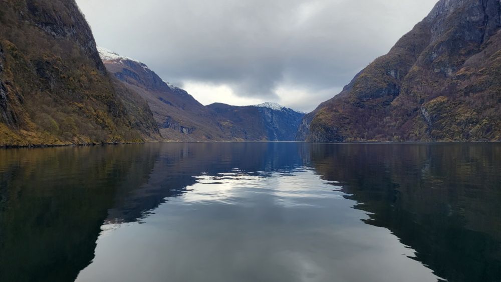 Steep mountains reflected in the calm waters of Nærøyfjord