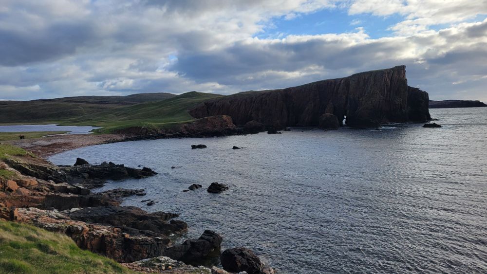 A dramatic coastline sloping up towards a vertical cliff at Hams on the island of Muckle Roe