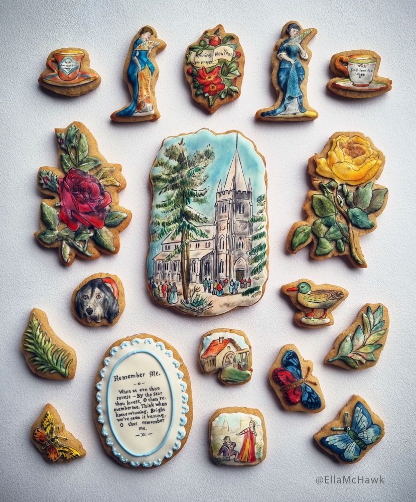 A collection of 18 biscuits of different sizes and shapes. In the centre is a large rectangular biscuit with rounded edges, painted with a snowy church scene. Flanking that biscuit are two large roses in shades of yellow and magenta. At the top corners of the set are two tiny teacups: one features spindly text that reads 'Think of me when far away', and the other says 'With fond love for thee'. The other biscuits in the set include: small butterflies in vivid shades of red, blue, yellow, and orange; leaves; a duck; a Basset hound; tiny figures in historical dress; a water mill scene; a decorative oval with a short verse titled 'Remember me'; and a bouquet adorned with a banner that reads 'Wishing you a Happy New Year'.