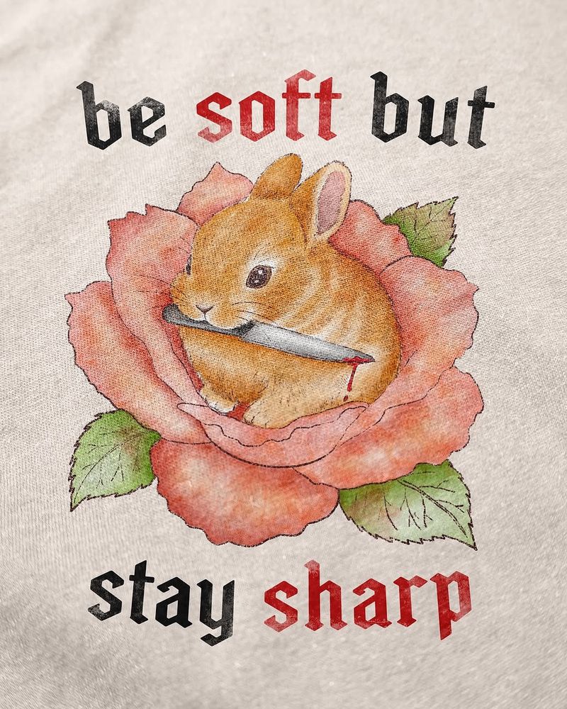 be soft by stay sharp
a bunny holding a knife in their mouth in a flower