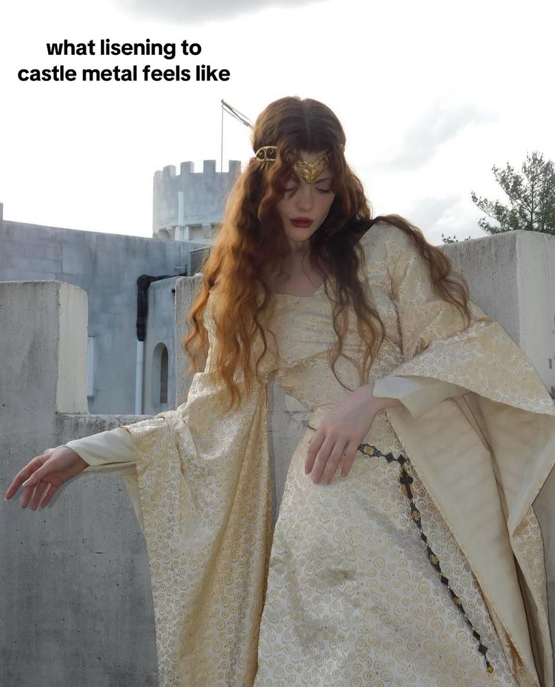a woman in a medieval dress stands in front of a castle 