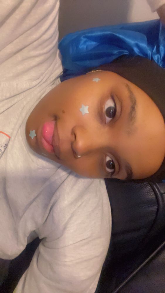 an absolute baddie wearing a blue bonnet, blue star shaped pimple patches and a gray sweatshirt 