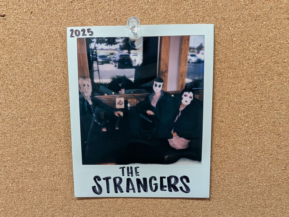 Image of a group of people in masks labeled THE STRANGERS