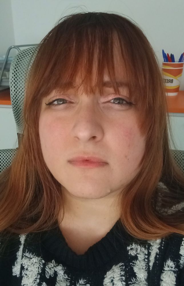 A woman, squinting at the camera in confusion. She's wearing light makeup, the same she has been wearing every day for the past year. Her bangs are slightly dirty, which could be what threw her male colleague.