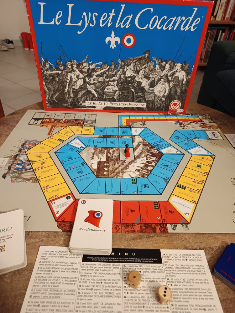 Plateau de jeu "le lys et la cocarde, le jeu de la révolution" avec un plateau se présentant comme un jeu de l'oie, des pions rouge et noir et des cartes "révolutionnaires" 