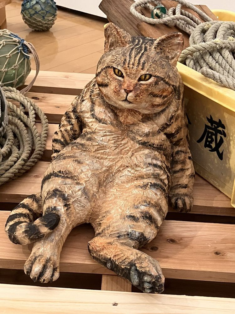 ふてぶてしく座った猫の木彫りの像