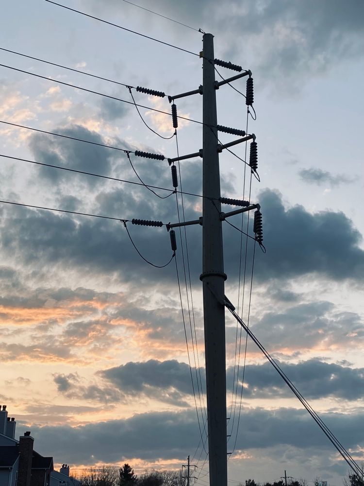 tall power transmission tower silhouetted against a sunset sky