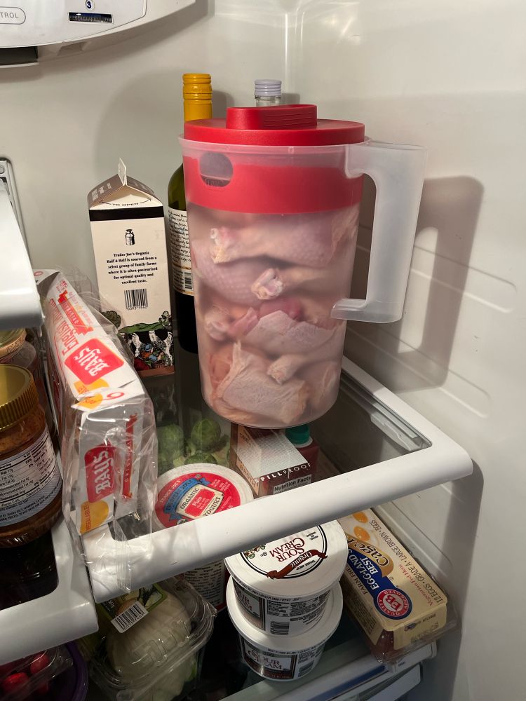 Chicken brining in a plastic pitcher